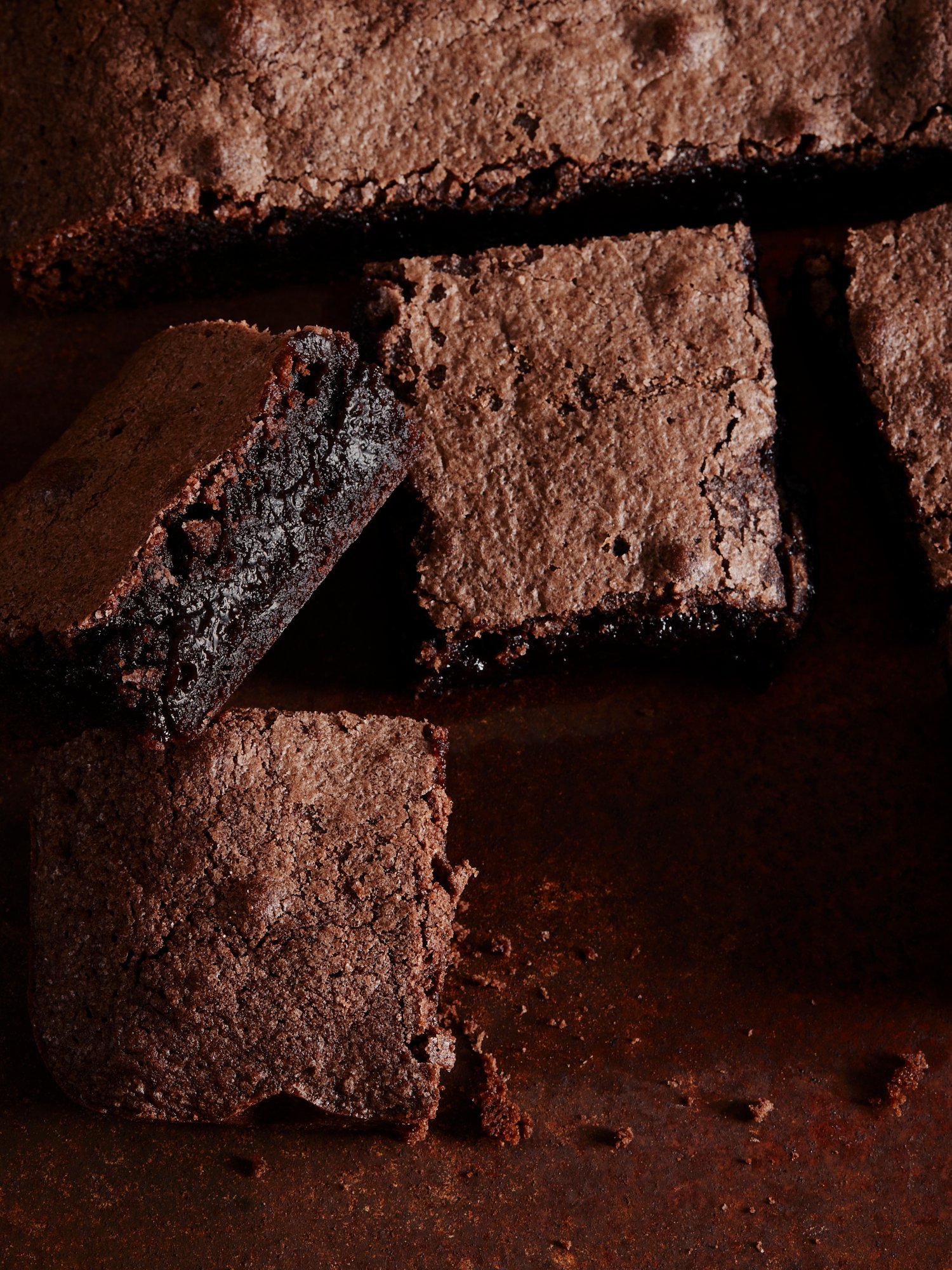 Cut brownies stacked close to the lens, their dense centres showing, Chocolate by Hannah Caldwell
