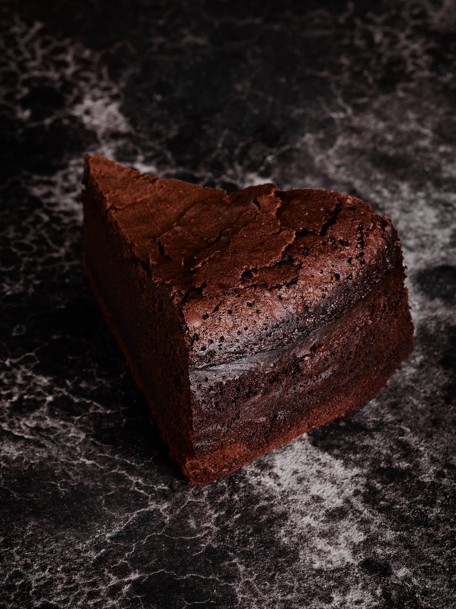 A single wedge of flourless chocolate cake on dark marble, Chocolate by Hannah Caldwell