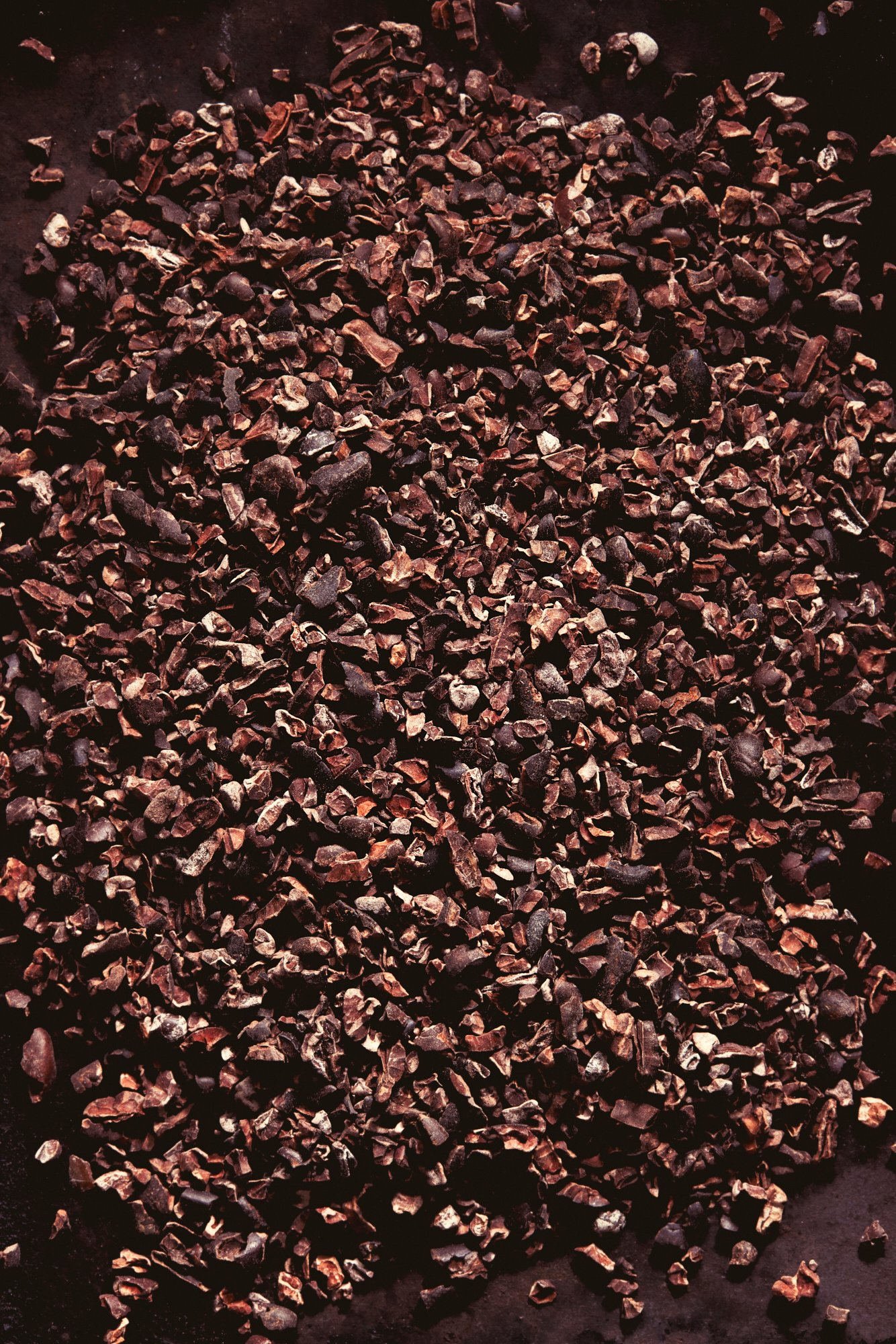 A drift of cracked cocoa nibs across a dark surface, Chocolate by Hannah Caldwell