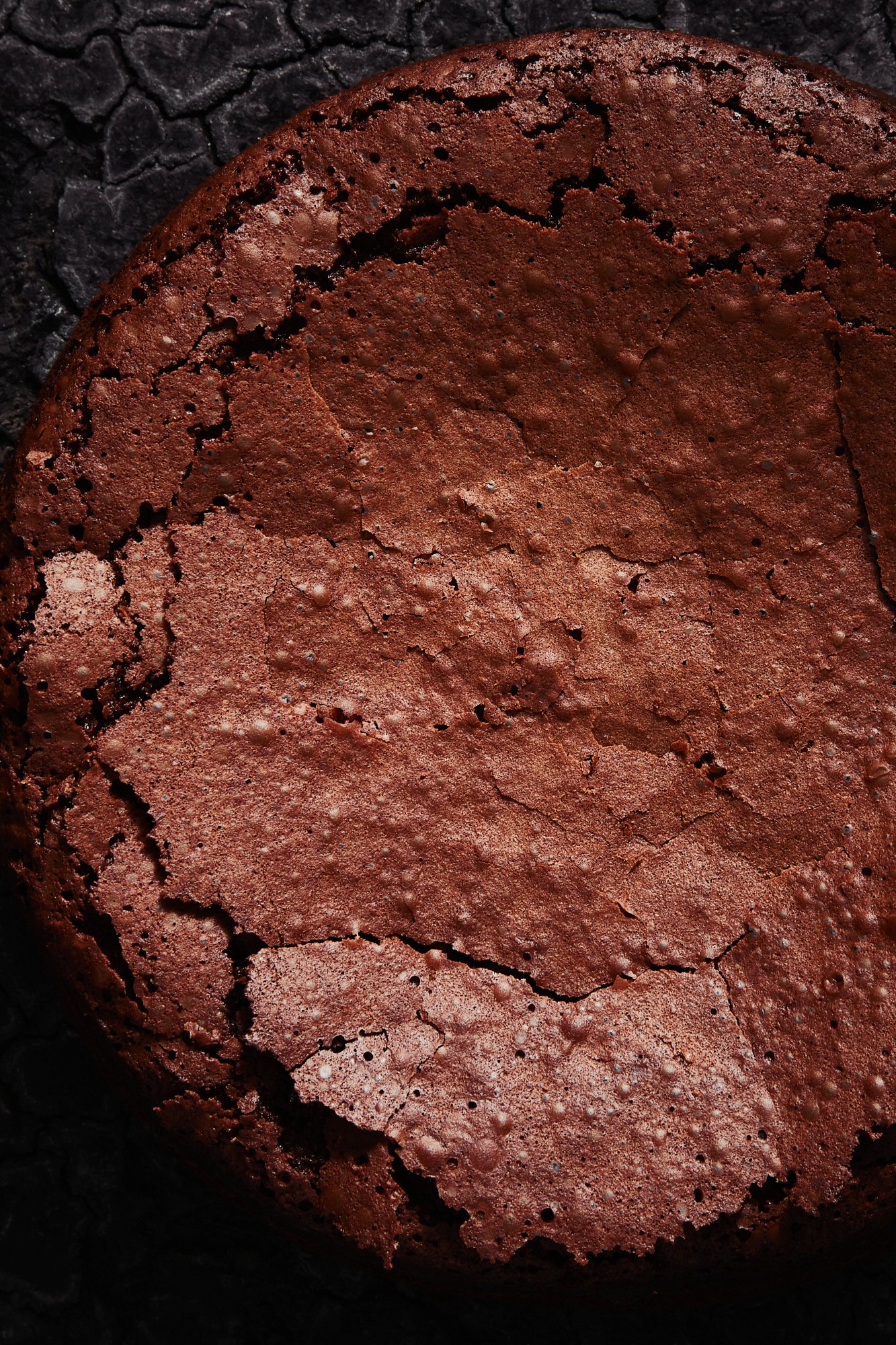 A whole flourless chocolate cake seen from above, its crust split open, Chocolate by Hannah Caldwell
