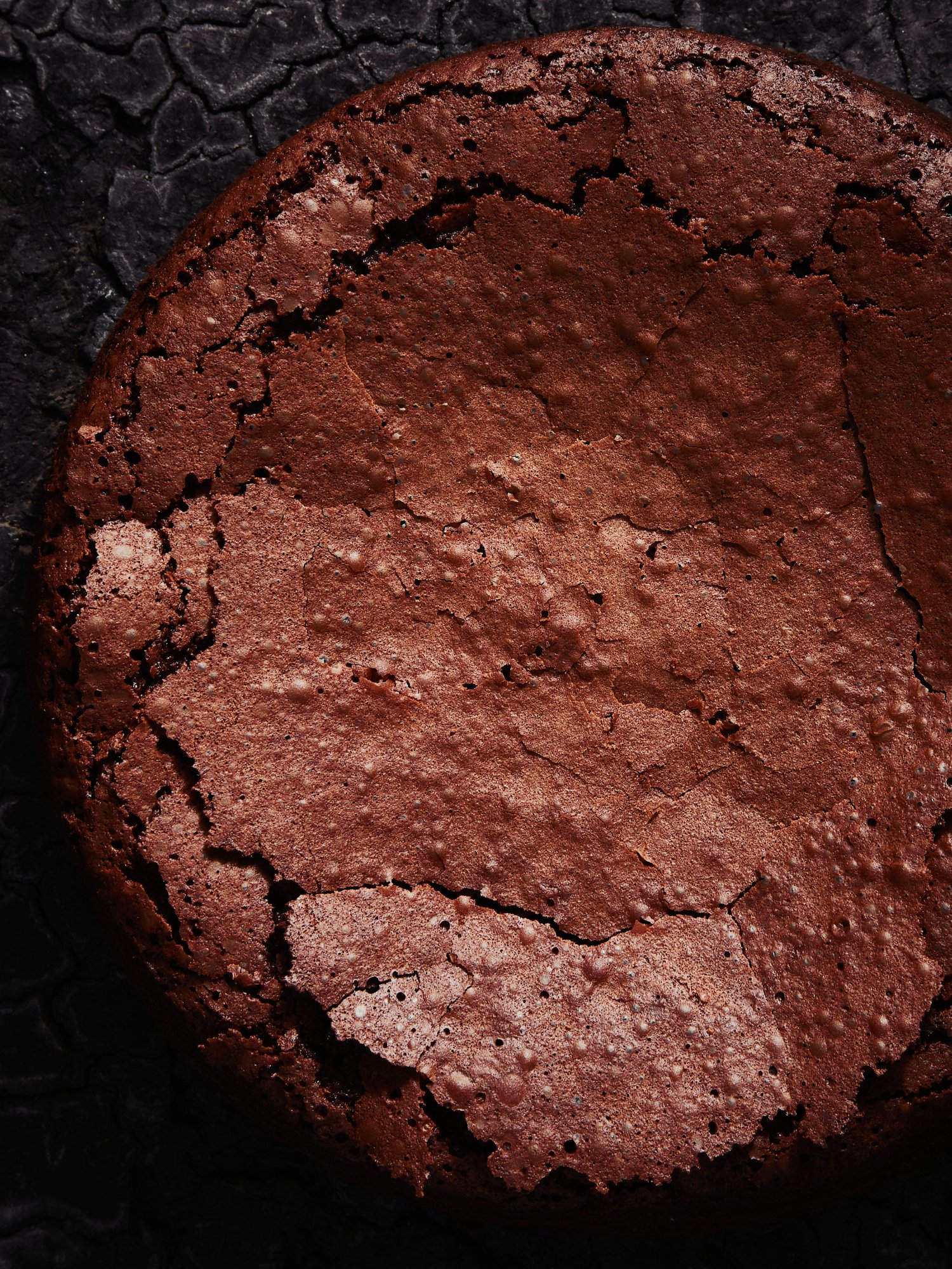 A whole flourless chocolate cake seen from above, its crust split open, Chocolate by Hannah Caldwell