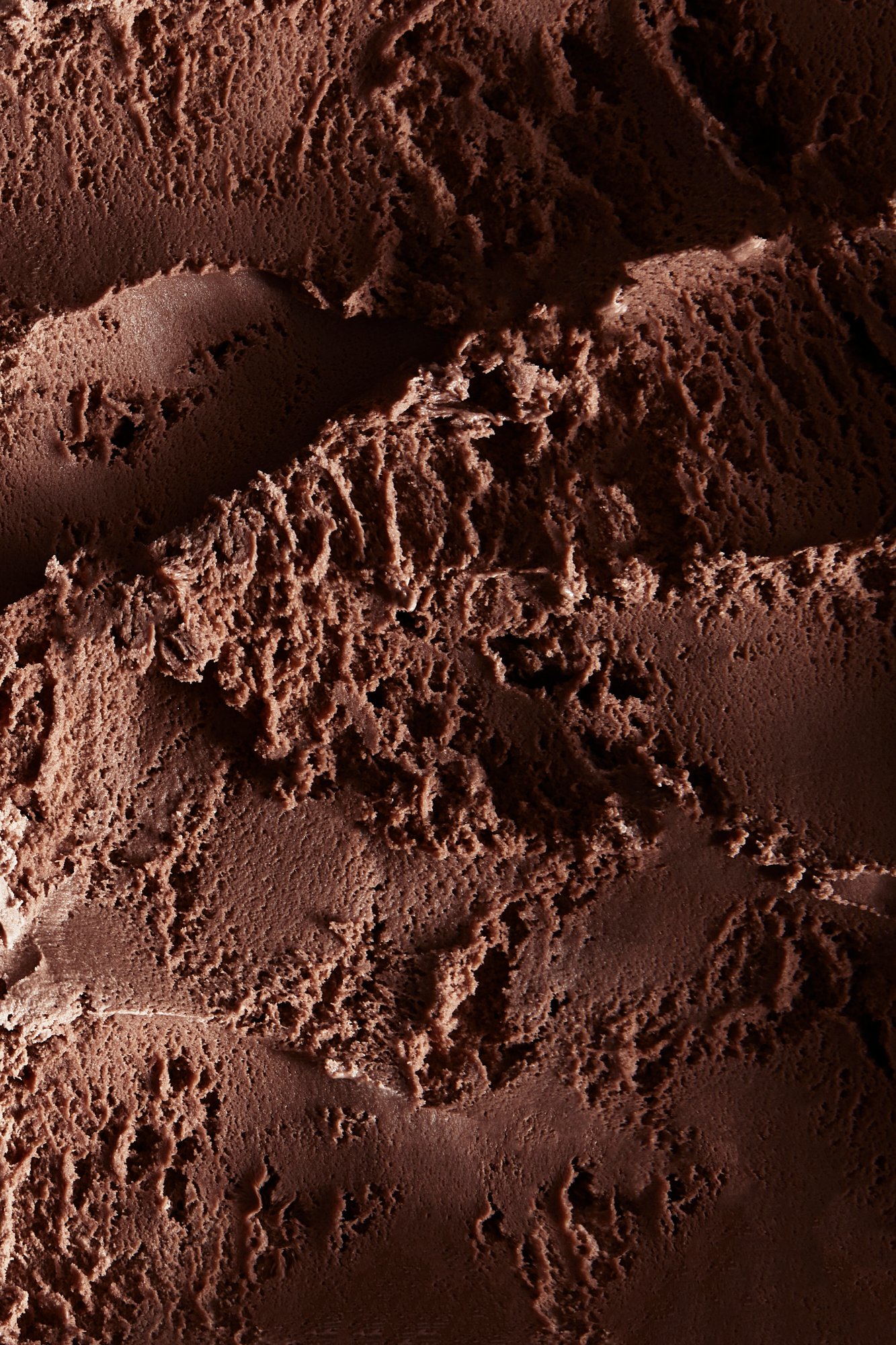 The scraped surface of chocolate ice cream held in soft light, Chocolate by Hannah Caldwell