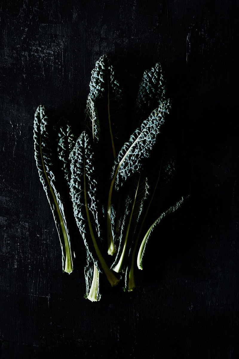 A bunch of cavolo nero against black, RAW by Hannah Caldwell
