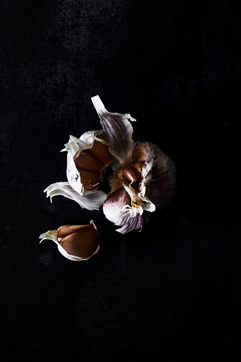A garlic bulb opened with loose cloves, RAW by Hannah Caldwell
