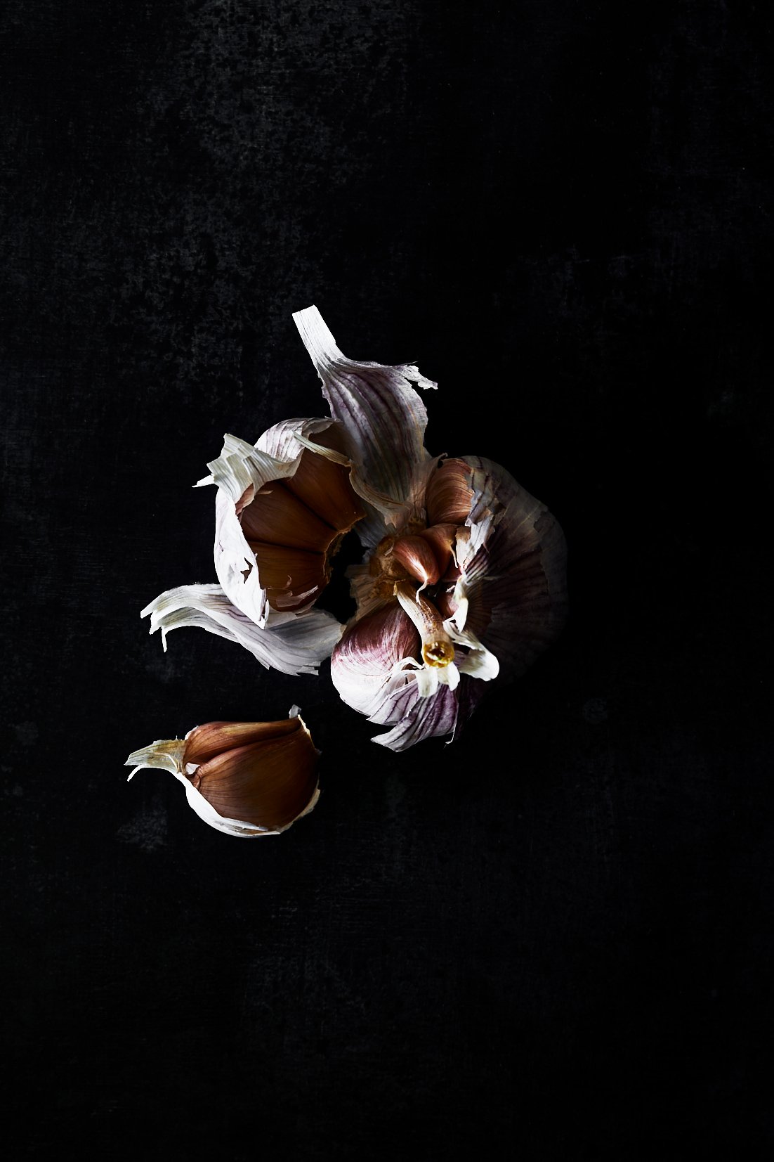 A garlic bulb opened with loose cloves, RAW by Hannah Caldwell
